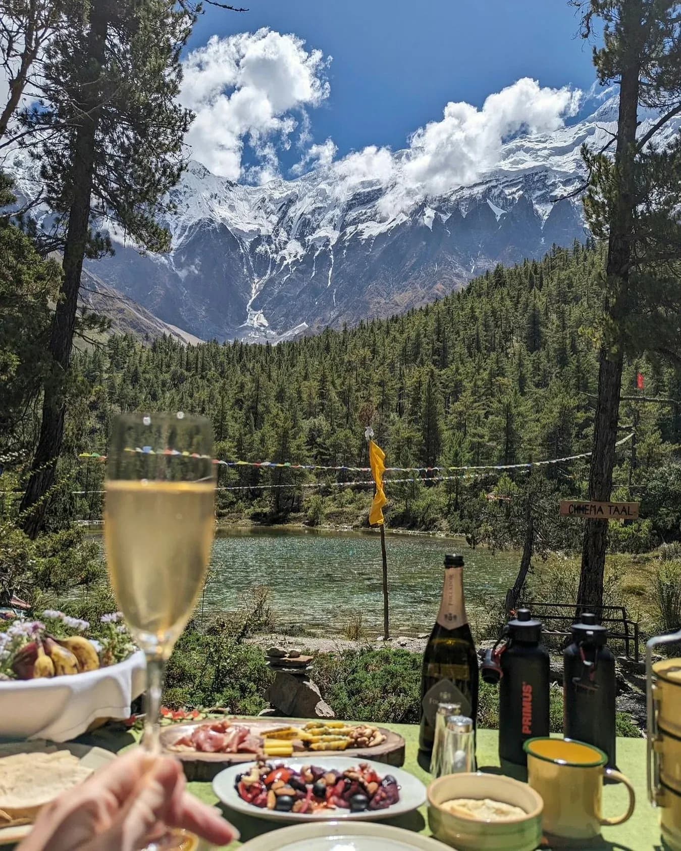 A picnic lunch with sparkling wine beside Chhema Taal, a forest lake below snow-covered peaks