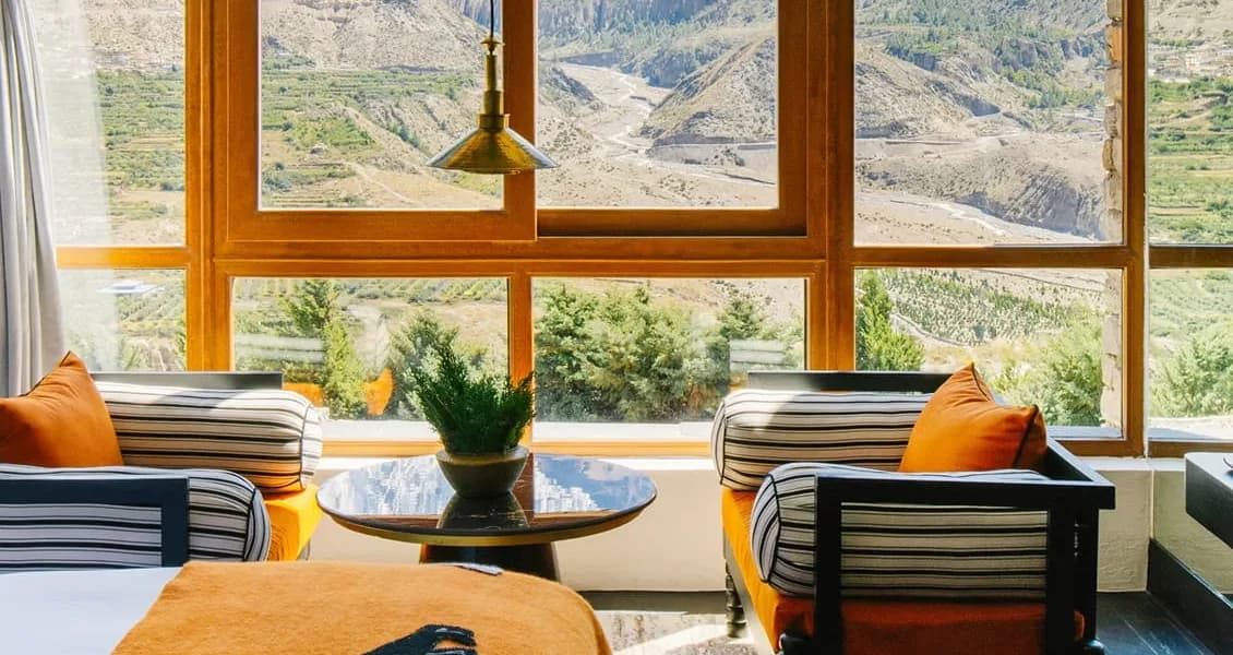 A suite at Shinta Mani Mustang, with armchairs facing floor-to-ceiling windows over the Kali Gandaki valley