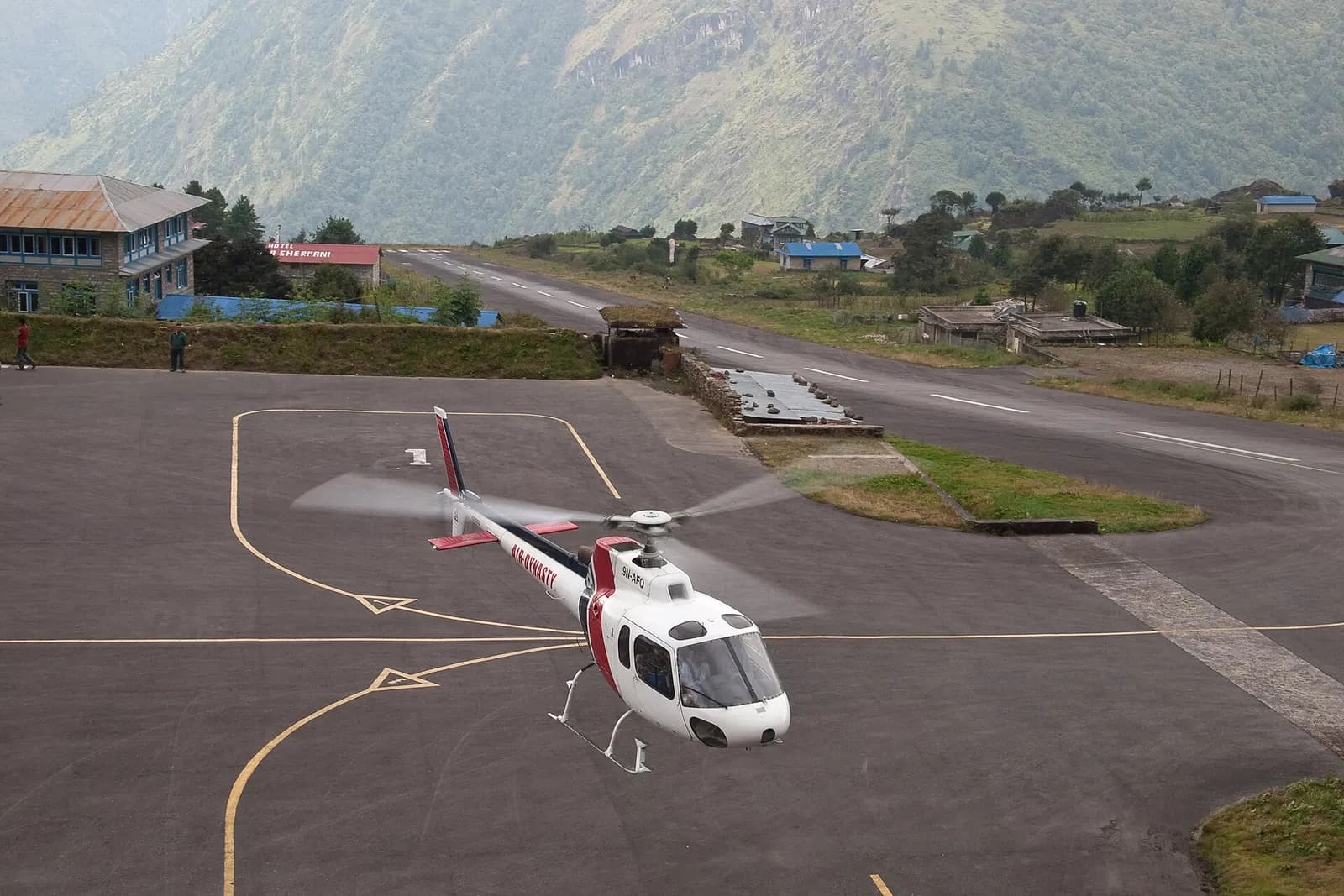 A helicopter on the apron beside the runway at Lukla airport